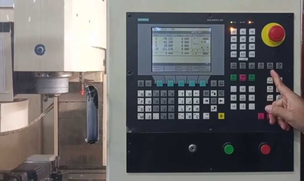 Operator using a CNC control panel beside a milling machine, the kind of controller replaced in an upgrade from Mach3